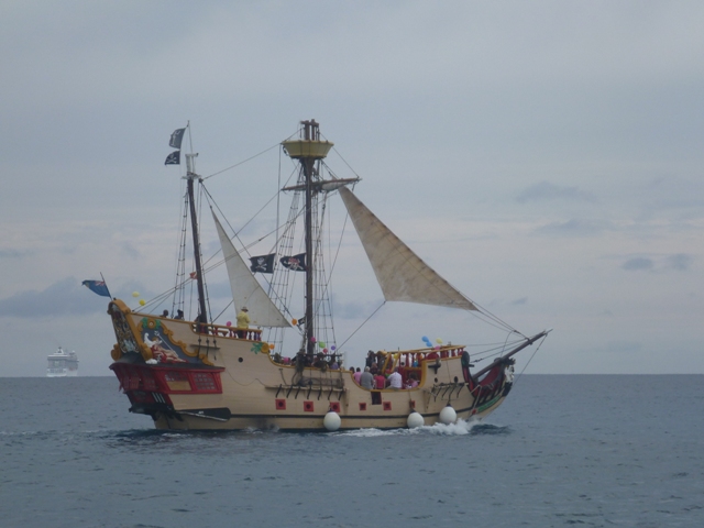 the local pirate ship passing while a cruise ships leaves